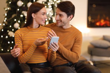 Mutlu çift cep telefonu kullanıyor ve evde konuşuyor.