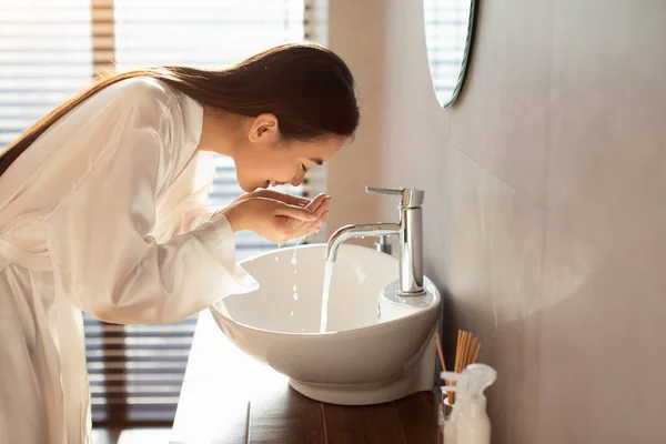 Ładna młody Azji kobieta w jedwabny szlafrok mycie twarzy — Zdjęcie stockowe