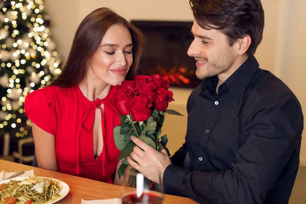 Jovem homem bonito dando rosas vermelhas para a mulher — Fotografia de Stock