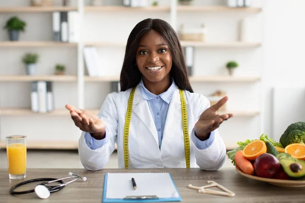 Concepto de nutrición saludable. Amistoso nutricionista negro dando consultas de pérdida de peso en línea, sentado en el lugar de trabajo —  Fotos de Stock