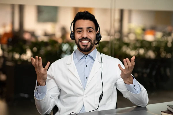 Lachende jonge knappe Midden-Oosten ingenieur of arts in hoofdtelefoon gebaren, kijk naar de camera — Stockfoto