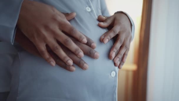 Sincere family love and care. Close up shot of african american man and woman caressing big pregnant belly, zoom in — kuvapankkivideo