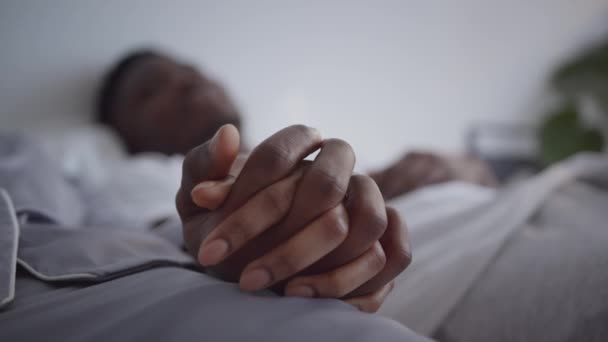 Conexión familiar. Primer plano de irreconocibles manos de pareja negra, hombre y mujer cariñosos tocándose en la cama — Vídeos de Stock
