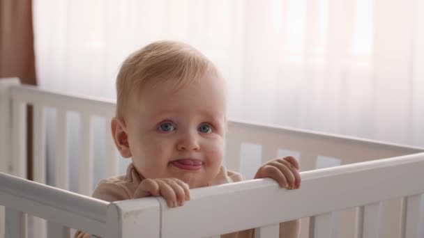 Bebek beşiğinde dikilirken ve yüzünü buruştururken yakın plan çekimleri. — Stok video