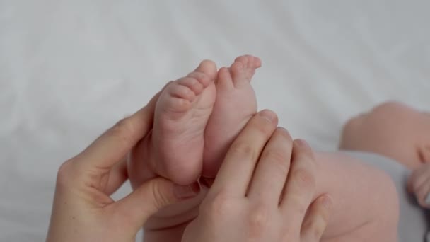 Уход за детьми. Крупный план любящей матери, играющей с новорожденными крошечными ножками — стоковое видео