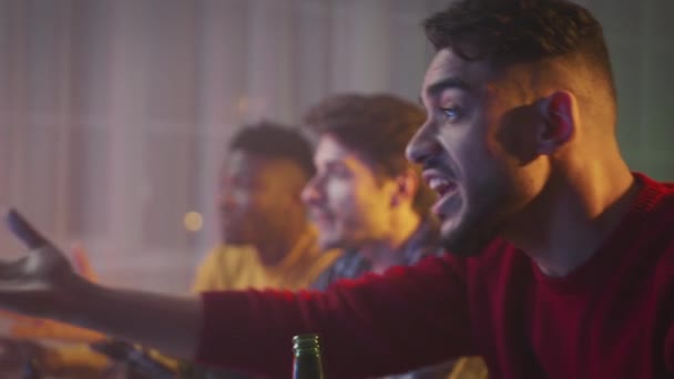 Emotional football match. Young middle eastern guy supporting his favorite soccer team, watching game with friends on tv — Video