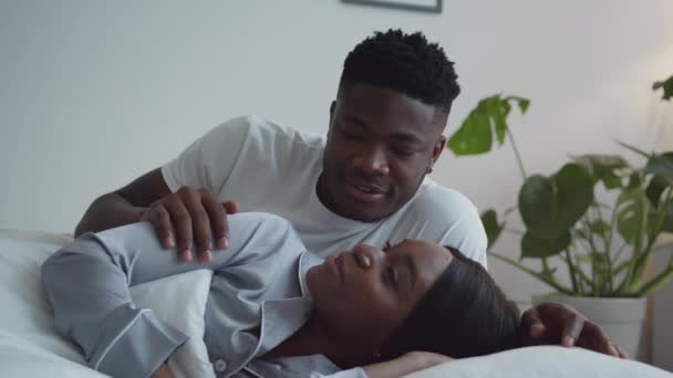 Good morning, sweetheart. Young loving african american man waking up his lovely wife, lying and talking together in bed — Stok Video