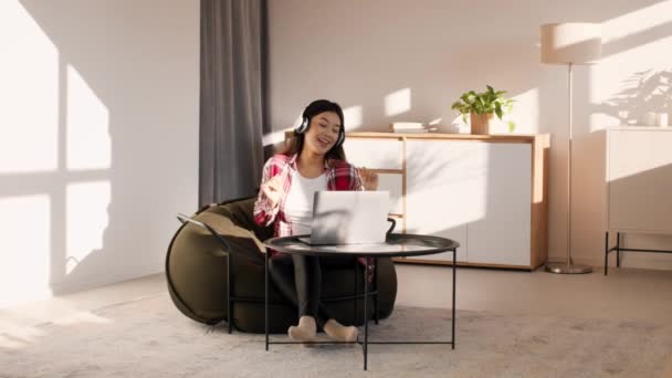 Mulher asiática ouvir música no laptop usando fones de ouvido em casa — Vídeo de Stock