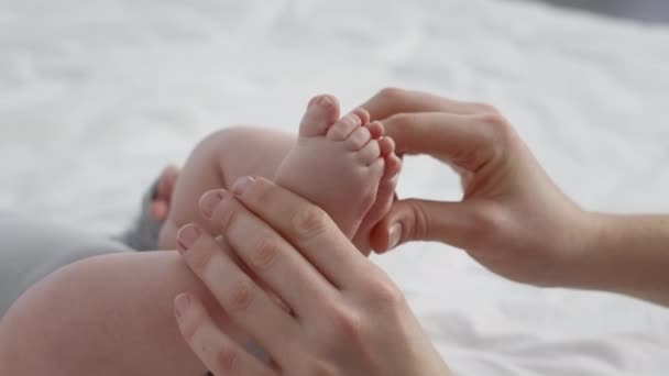 Concepto de cuidado materno. Mamá cariñosa tocando las pequeñas piernas de su bebé recién nacido — Vídeos de Stock
