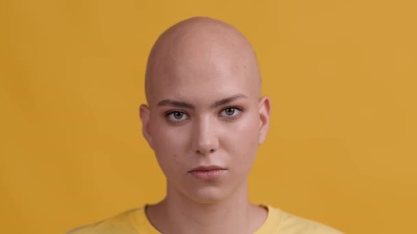Headshot Of Serious Bald-Headed Woman Looking At Camera, Yellow Background — Video
