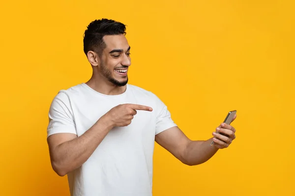 Happy arabic guy pointing at mobile phone screen — Fotografia de Stock