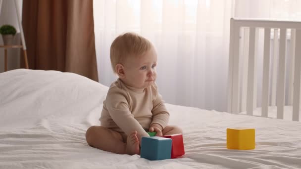 Dětský vývoj. Roztomilé dítě hraje s barevnými stavebními bloky na posteli — Stock video