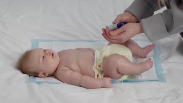 Çocuk bakımı konsepti. Umursayan Anne, yeni doğan bebek tenine nemlendirici krem sürüyor. — Stok video