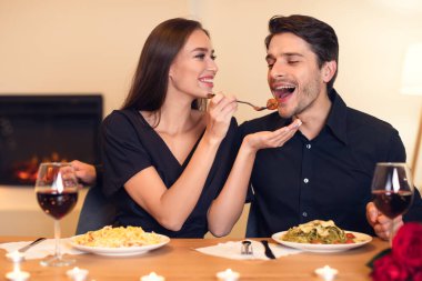 Smiling woman feeding her man with pasta