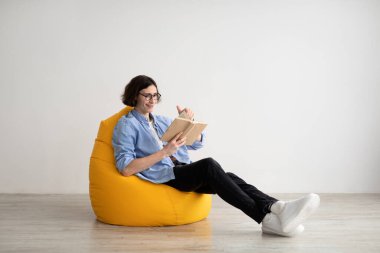 Rahat adam kitap okurken armut koltukta boş boş duvarda oturuyor. Hafta sonu eğlence konsepti
