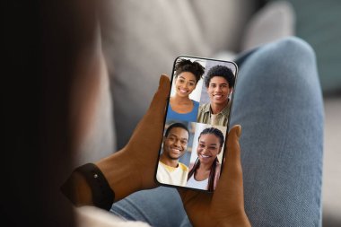 Lady holding smartphone with happy black people faces on screen