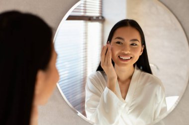 Young beautiful korean lady using moisturising face cream