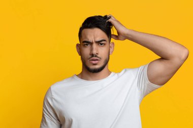 Confused middle eastern man touching his head