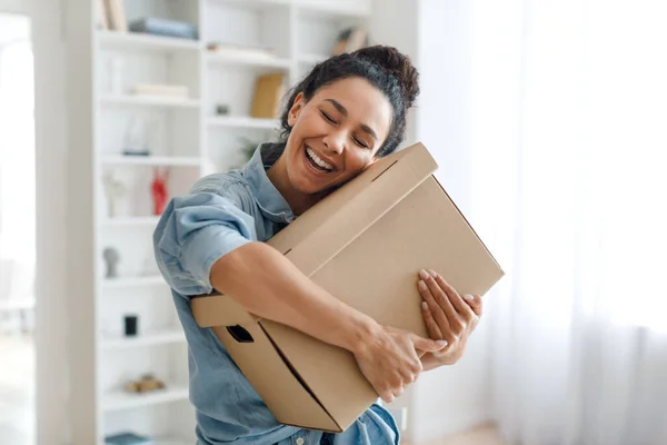 Mujer feliz comprador abrazando entrega caja de cartón de pie en casa —  Fotos de Stock