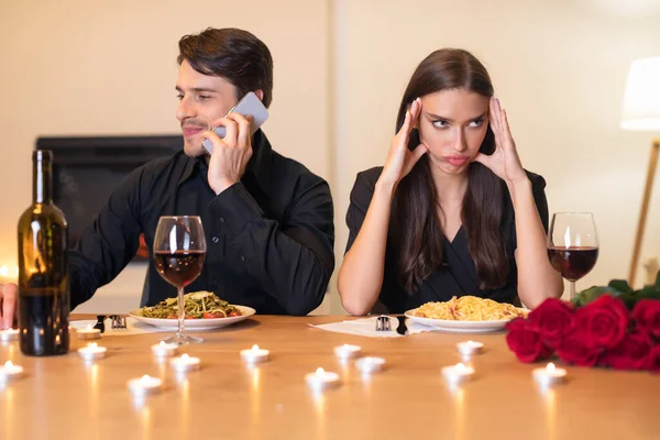 Nieszczęśliwa kobieta znudzona na randce, mężczyzna rozmawiający przez telefon — Zdjęcie stockowe