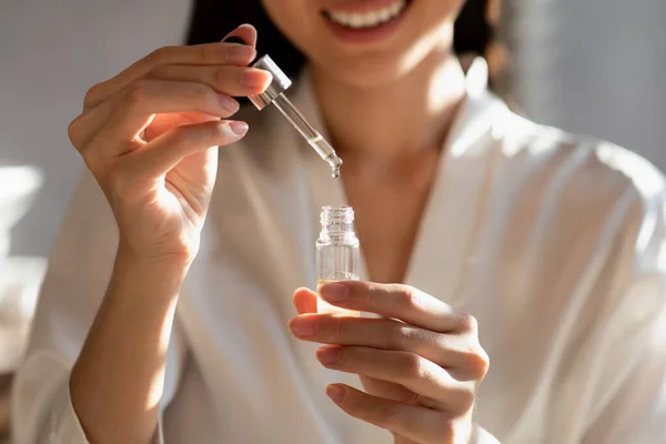 Unrecognizable smiling woman holding bottle with beauty product, closeup — Stock Fotó