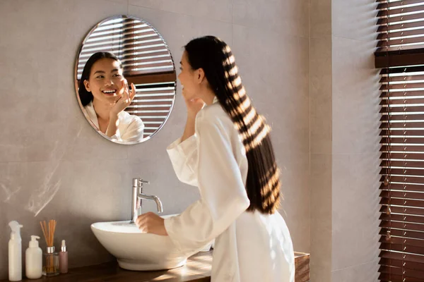 Voltar vista de feliz asiático mulher aplicando rosto cuidado produto — Fotografia de Stock