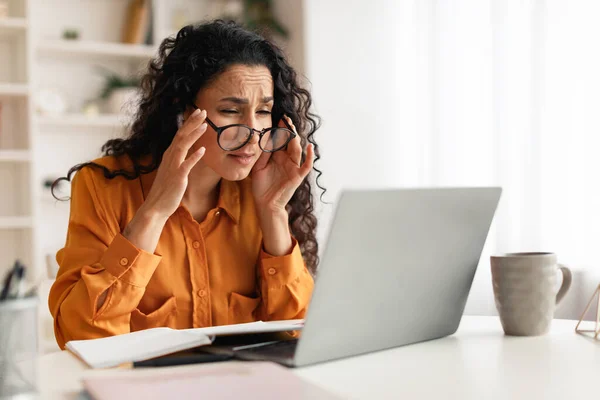 Vrouw met slecht gezichtsvermogen dragen bril kijken naar laptop binnen — Stockfoto