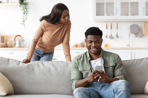 Enojado negro mujer viendo su novio charlando con damas —  Fotos de Stock
