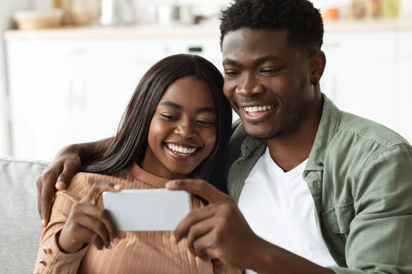 Щасливі афроамериканські коханці, які самовіддано користуються мобільним телефоном. — стокове фото