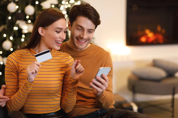 Boldog pár mobiltelefonnal és bankkártyával otthon — Stock Fotó