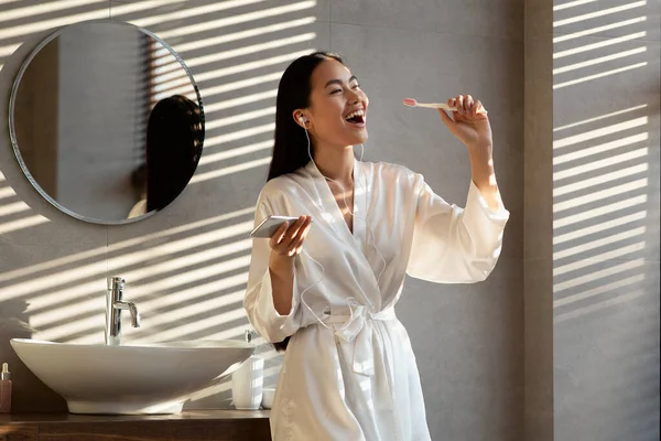 Mulher coreana feliz cantando enquanto escova os dentes no banheiro — Fotografia de Stock