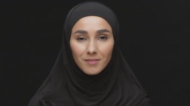 Kameraya gülümseyen geleneksel tesettürlü Ortadoğulu Müslüman bayanın stüdyo portresini kapatın.