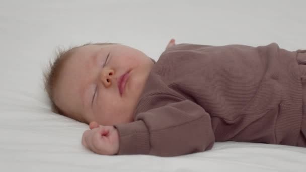 Крупный план Очаровательный новорожденный ребенок мирно спит на кровати дома — стоковое видео