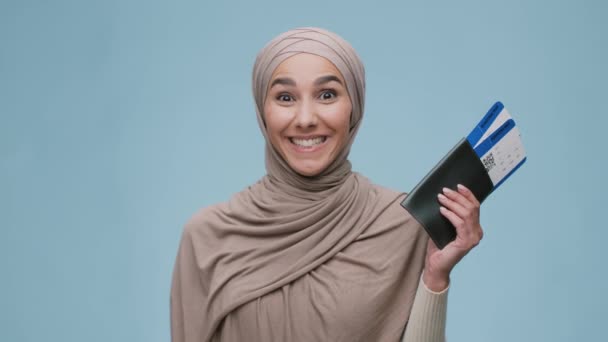 Молодая возбужденная мусульманка в хиджабе с паспортами и билетами на самолет, предвкушая будущие путешествия, улыбаясь в камеру — стоковое видео