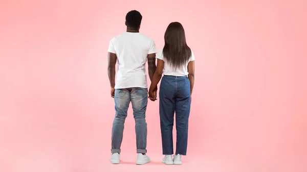 Selbstbewusstes Paar steht vor rosa Studiohintergrund vor der Kamera — Stockfoto