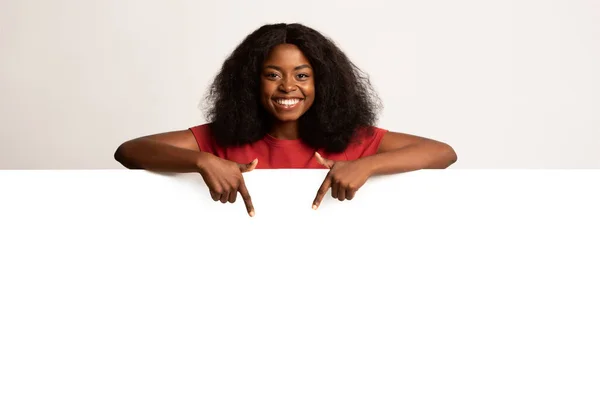 Vreugdevolle zwarte vrouw wijzen neer op kopieerruimte op lege reclamebord — Stockfoto