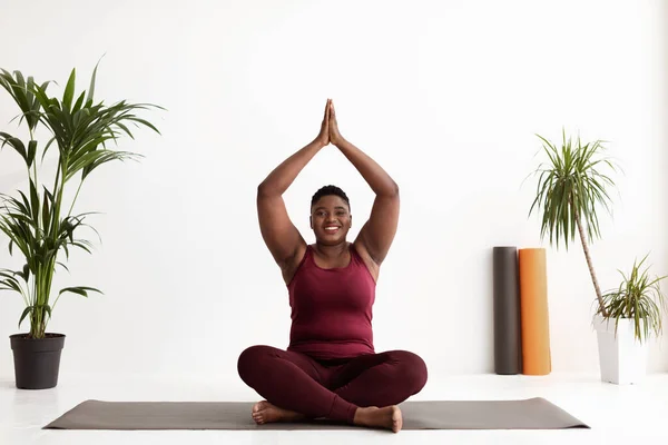 Mujer afroamericana flexible con sobrepeso meditando en el estudio de yoga —  Fotos de Stock