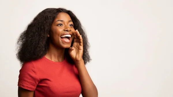 Позитивная молодая чернокожая женщина с рукой у рта делает объявление — стоковое фото