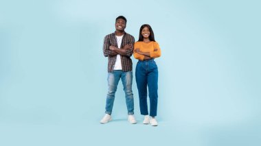 Mavi stüdyo arka planında kollarını kavuşturmuş kendine güvenen bir çift.