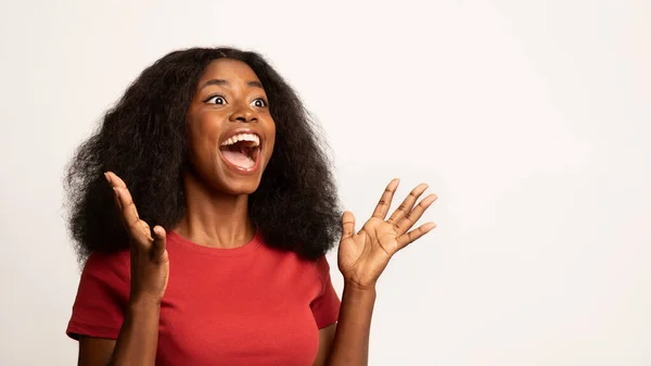 Большой сюрприз. Сверхрадостная черная женщина, поднимающая руки и восклицающая с волнением — стоковое фото