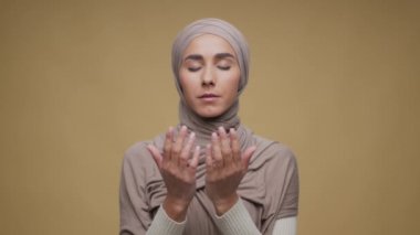 İnanç kavramı. Geleneksel tesettüre bürünmüş, Tanrı 'ya dua eden Ortadoğulu Müslüman kadının stüdyo portresi.