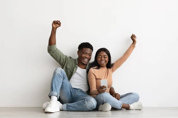 Joyeux couple noir jouant ensemble en ligne, en utilisant un smartphone — Photo