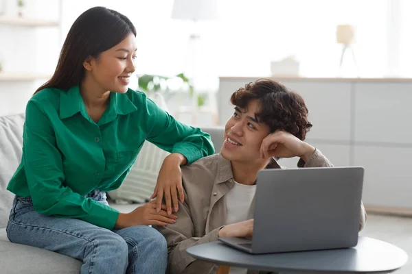 Happy young Asian couple using laptop, watching videos or shopping online, checking social media at home — Stock Photo, Image
