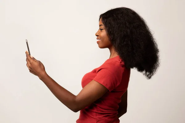 Identyfikacja biometryczna. Uśmiechnięta czarna kobieta za pomocą aplikacji rozpoznawania twarzy na smartfonie — Zdjęcie stockowe