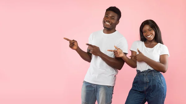 Emocionada pareja negra señalando a un lado el espacio libre de copia, panorama —  Fotos de Stock