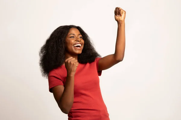 Сверхрадостная Черная женщина, поднимающая сжатые кулаки и восклицающая от волнения — стоковое фото