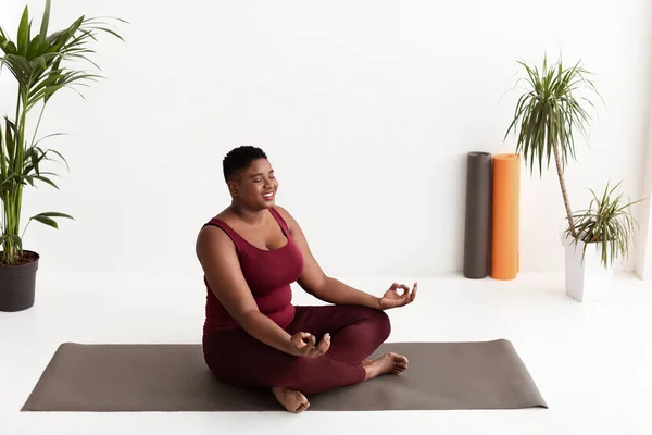 Señora negra grasa pacífica en ropa deportiva que tiene práctica de yoga —  Fotos de Stock