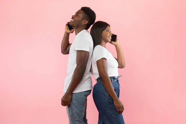 Akıllı telefonlardan konuşan Afro-Amerikan çift, pembe stüdyo duvarı. — Stok fotoğraf
