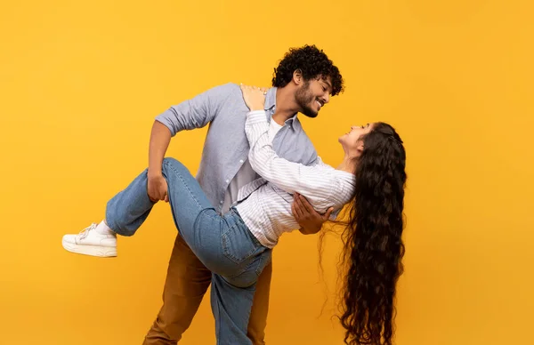Радісне індіанське подружжя, що любить танцювати і дивитися один на одного, веселитися на жовтому фоні, вільному просторі, з іншого боку. — стокове фото