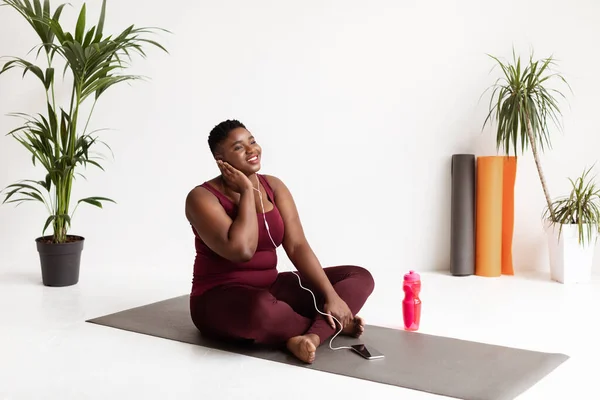 Emocionante mujer africana con sobrepeso disfrutando de la música mientras entrena —  Fotos de Stock
